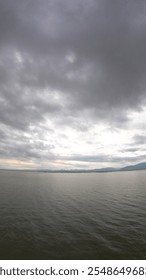 Dramatic sky over the lake with clouds and mountains in the background