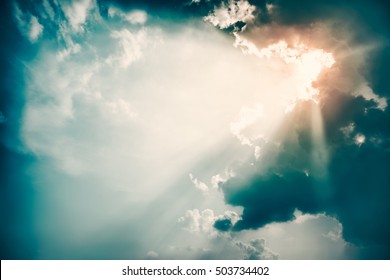 Dramatic Sky and Sun Rays Background. Stormy Clouds in Dark Sky. Sunbeams Light and Moody Cloudscape. Toned and Filtered Photo with Copy Space.