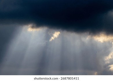 Dramatic sky with sunbeams shining through dark storm clouds. Beautiful natural light phenomenon creating contrast between darkness and hope. Ideal for nature backgrounds, inspirational themes, enviro - Powered by Shutterstock - Get 15% off with code: PIKWIZARD15