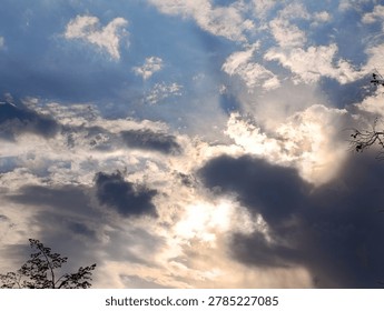 Dramatic sky with sunlight filtering through dark and white clouds