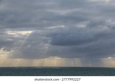 Dramatic sky with sunrays shining through dark clouds over the ocean near Margaret River in Western Australia