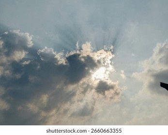 Dramatic sky view with sunlight breaking through thick clouds. Sun rays spread across the sky, creating a stunning visual effect.