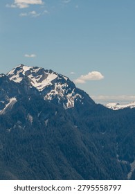 Dramatic snow-capped alpine mountain under a vast blue sky above Fraser Valley near Chilliwack, BC, Canada.