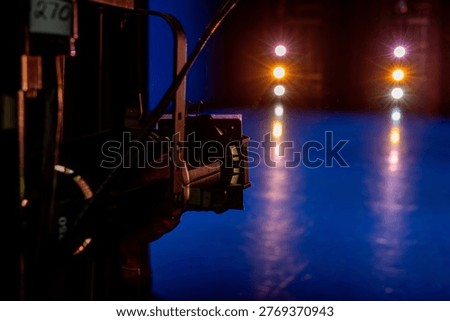 A dramatic stage environment illuminated by vibrant professional lighting, featuring warm spotlights, cool blue floor reflections, and the technical equipment that shapes a performance space. The images capture the behind‑the‑scenes atmosphere of a recital or theatrical production, highlighting the interplay of color, shadow, and precision lighting design. Visible fixtures, beams, and reflections emphasize the craft of stage technology and the mood it creates before performers step into the light. These photos convey anticipation, artistry, and the quiet intensity of a venue preparing for music, dance, or dramatic storytelling. Ideal for themes related to performing arts, stagecraft, lighting design, theatre production, concerts, rehearsals, creative industries, and event environments.
