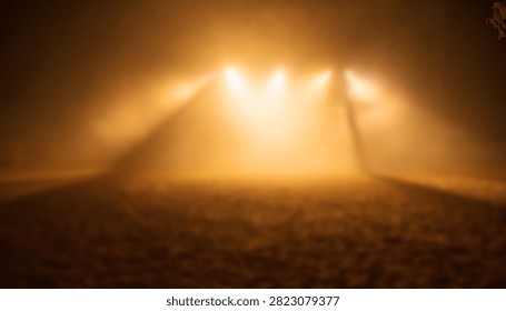 Dramatic stage lighting setup with intense golden beams cutting through dense fog creating a mysterious and atmospheric concert or theater environment