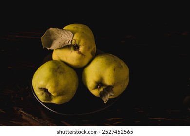 A dramatic still life of freshly picked quinces, captured in low-key chiaroscuro lighting, highlighting the rich textures and natural beauty of the fruit - Powered by Shutterstock