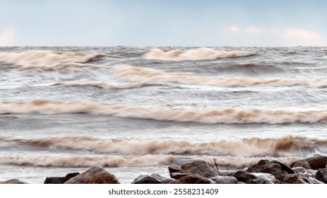 dramatic storm in the Baltic Sea, large waves crashing against the shore, blurred, unclear contours, rocky shore of Vidzeme, Thuja, Latvia