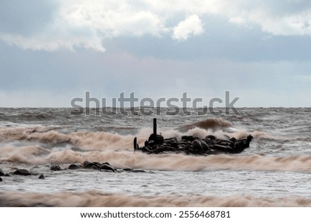 dramatic storm in the Baltic Sea, large waves crashing against the stone pier, blurred, unclear contours, rocky shore of Vidzeme, Thuja, Latvia