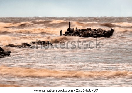 dramatic storm in the Baltic Sea, large waves crashing against the stone pier, blurred, unclear contours, rocky shore of Vidzeme, Thuja, Latvia