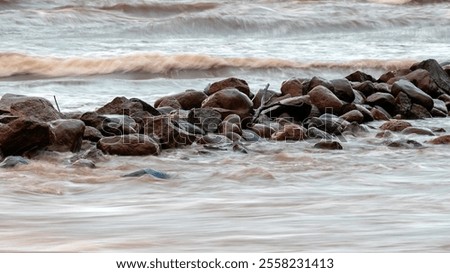 dramatic storm in the Baltic Sea, large waves crashing against the stone pier, blurred, unclear contours, rocky shore of Vidzeme, Thuja, Latvia