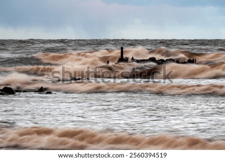 dramatic storm in the Baltic Sea, large waves crashing against the stone pier, blurred, unclear contours, rocky shore of Vidzeme, Thuja, Latvia