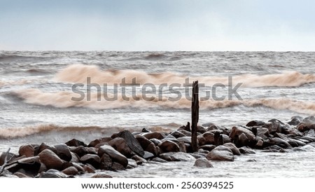 dramatic storm in the Baltic Sea, large waves crashing against the stone pier, blurred, unclear contours, rocky shore of Vidzeme, Thuja, Latvia