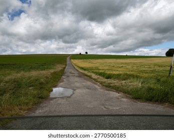 Dramatic storm clouds approaching over a wide green summer field under a deep blue sky