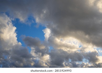 Dramatic Storm Clouds with Blue Sky Breaking Through. Dark storm clouds gathering while patches of vivid blue sky remain visible. A dramatic weather scene capturing the contrast between sunlight and approaching rain, perfect for climate, weather forecast, and nature themes.