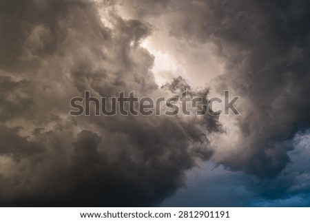 Dramatic storm clouds with a bright opening of light in the center, concept of hope, silver lining and breakthrough.