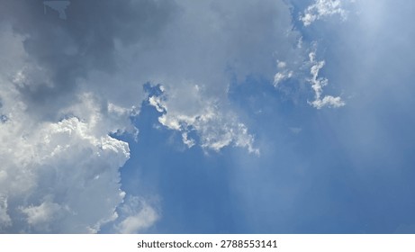 Dramatic storm clouds forming in blue sky with sunbeams background.