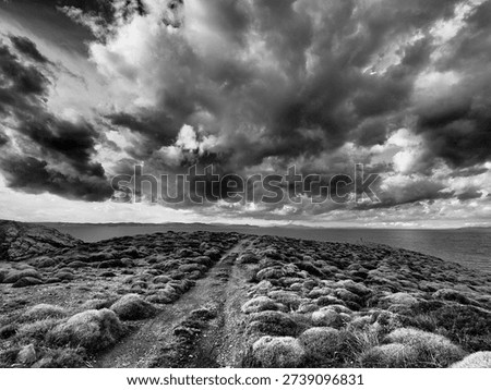 Dramatic storm clouds gathering above a rugged Mediterranean coastline in Greece. Stylised landscape with strong contrast and textured skies, suitable for weather editorial, climate change features, e