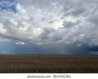 Dramatic storm clouds gathering over vast rural field landscape