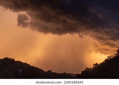 Dramatic storm clouds  with an intense rain lit by the setting sun, Croatia