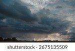 Dramatic storm clouds loom over flat rural landscape. Dark and heavy clouds create an ominous and intense atmosphere during daytime.