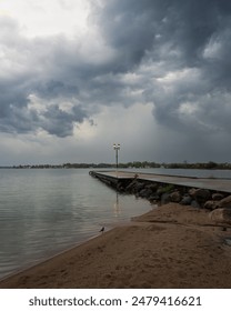 The dramatic storm clouds loom over top a lonely light post on a pier in Orillia, Ontario, Canada