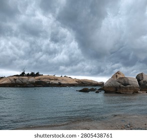 Dramatic Storm Clouds Over Coastal Granite Rocks and Calm Sea Landscape