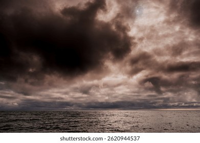 Dramatic storm clouds over dark sea with moody light and textured water surface. Atmospheric seascape conveying tension, nature power, mystery and calm before the storm - Powered by Shutterstock - Get 15% off with code: PIKWIZARD15