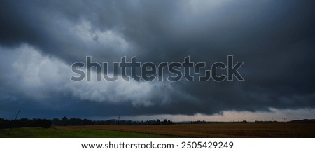 Dramatic storm clouds over the field, creating threatening atmosphere in countryside