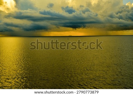 Dramatic storm front over golden ocean waters at sunset with distant fishing boat