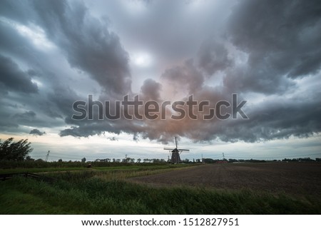 Dramatic stormclouds over a lone windmill in the countryside of Holland