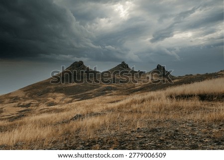 Dramatic stormy sky above dry grass steppe and rocky hills at Khorgoy Cape on Lake Baikal, Olkhon District, Irkutsk Oblast, Russia, wilderness travel scene