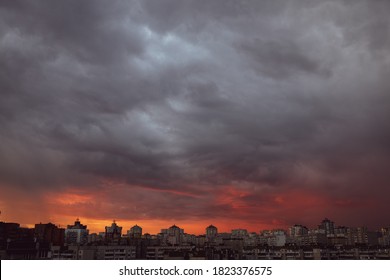 Dramatic stormy sunset sky with clouds over city skyline background.