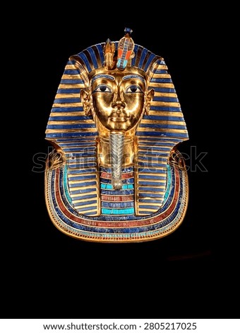 Dramatic studio lighting illuminates the iconic gold and lapis lazuli funerary mask of Tutankhamun isolated on black