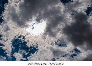 Dramatic sun breaking through dark, heavy storm clouds. Ethereal light of the sun behind dramatic stormy cloud formations.