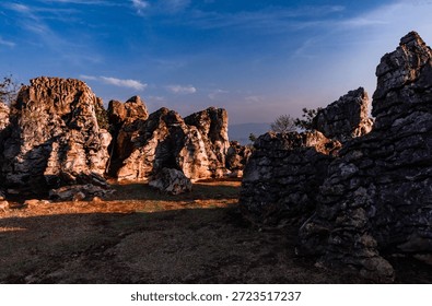 Dramatic Sun Light on Rugged Limestone Rock Formations
A scenic view of large, ancient limestone rocks bathed in dramatic sunlight and shadow under a blue sky, suitable for travel or nature themes