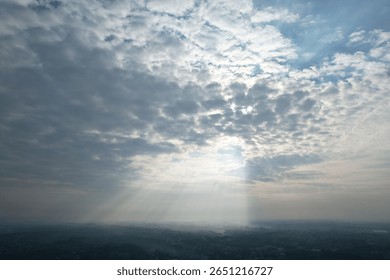 Dramatic sun rays breaking through thick clouds over a misty landscape – aerial view
A beautiful aerial view of the morning sun rays piercing through dense clouds, casting dramatic light over a foggy 