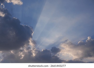 Dramatic Sun Rays Breaking Through Dark Clouds in a Blue Sky