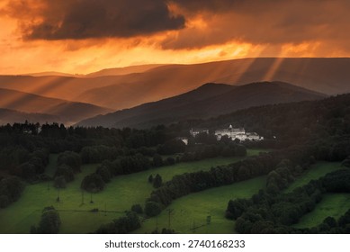 Dramatic sun rays breaking through dark, heavy clouds over the Priessnitz Spa resort in Jesenik, Czech Republic, creating a moody atmosphere.