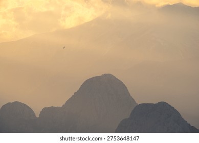 Dramatic sun rays breaking through clouds over the Bey Mountains and the Mediterranean Sea during sunset near Antalya, Türkiye.