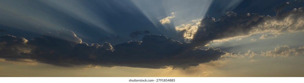 Dramatic Sun Rays Breaking Through Clouds in Panoramic Sky Background. Dramatic cloudscape with radiant beams of light, ideal for backgrounds, banners, inspirational concepts, and nature-themed designs.
