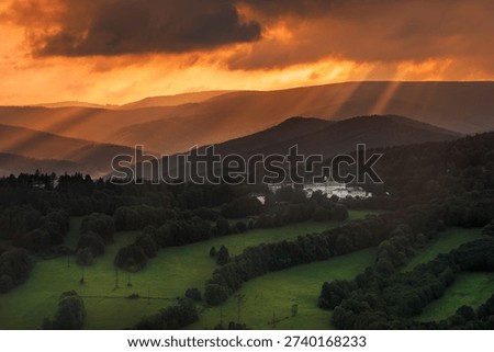 Dramatic sun rays breaking through dark, heavy clouds over the Priessnitz Spa resort in Jesenik, Czech Republic, creating a moody atmosphere.