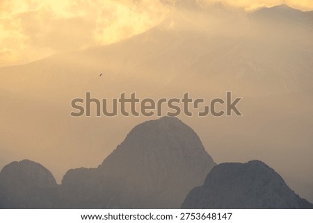 Dramatic sun rays breaking through clouds over the Bey Mountains and the Mediterranean Sea during sunset near Antalya, Türkiye.