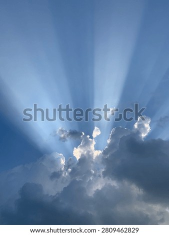 Dramatic Sun Rays Breaking Through Storm Clouds Against a Blue Sky