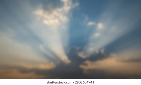 Dramatic sun rays pierce through dark clouds during a vibrant sunset, creating a beautiful atmospheric effect in the sky.