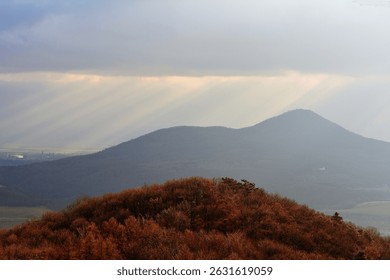 Dramatic Sun Rays Piercing Through Clouds Over Rolling Czech Hills in Morning
