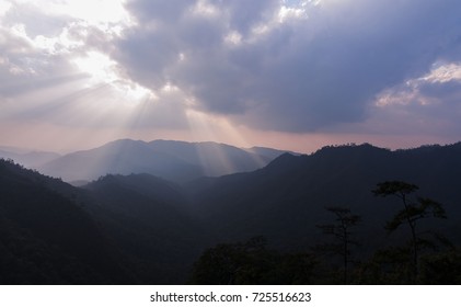 Dramatic sunbeam rays break through the cloud over mountain in tropical forrest at sunset