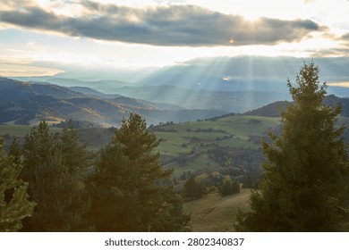 Dramatic sunbeams breaking through clouds over autumn mountain valley in Pieniny.
