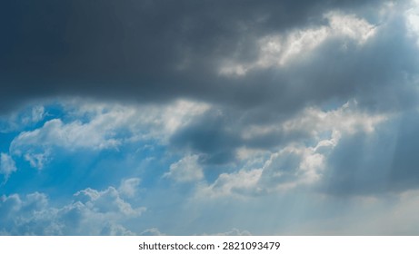 Dramatic sunbeams breaking through dark storm clouds under a vibrant blue sky