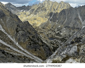 Dramatic sunlight illuminating a deep rocky alpine valley and mountain tarn in the High Tatras national park, Slovakia. View from Predne Solisko in Tatras mountains 
