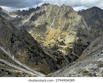 Dramatic sunlight illuminating a deep rocky alpine valley and mountain tarn in the High Tatras national park, Slovakia. View from Predne Solisko in Tatras mountains 
